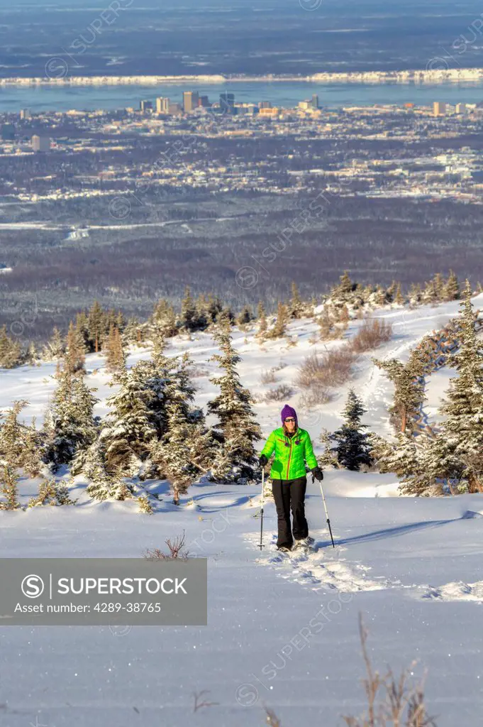 Woman snowshoeing at the Glen Alps area of Chugach State Park overlooking Anchorage on a sunny winter day, Southcentral Alaska, HDR