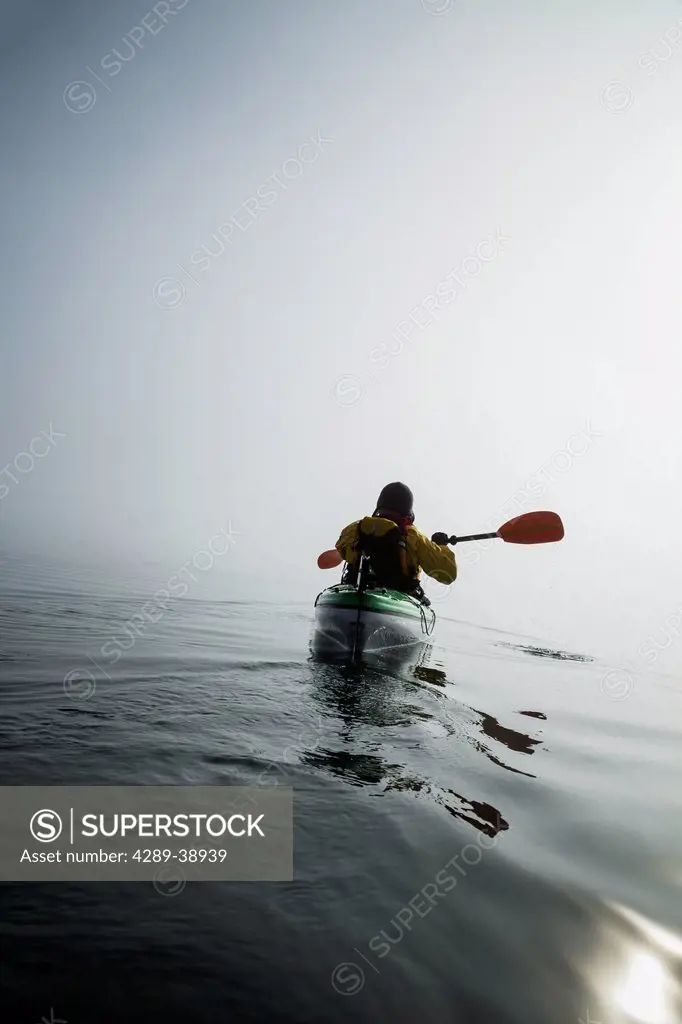 A sea kayaker paddles into thick fog on on a calm morning in Southeast Alaska's Stephens Passage. MR_ Ed Emswiler, ID#12172012A