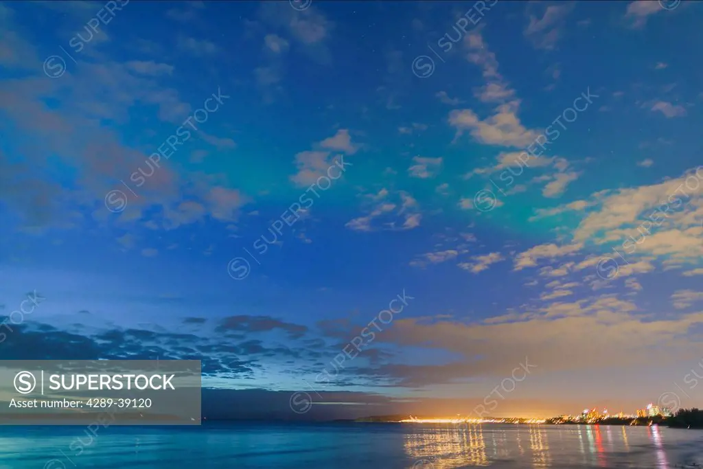 The lights of the Anchorage Skyline reflected in the waters of Knik Arm, Northern Lights in the sky above, early morning twilight, summer, Tony Knowle...