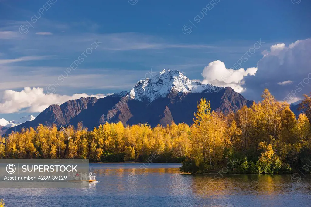 Two men fishing from a pontoon boat in Finger Lake, snow capped Pioneer Peak in the background, fall folliage, Wasillia, Southcentral Alaska, USA.