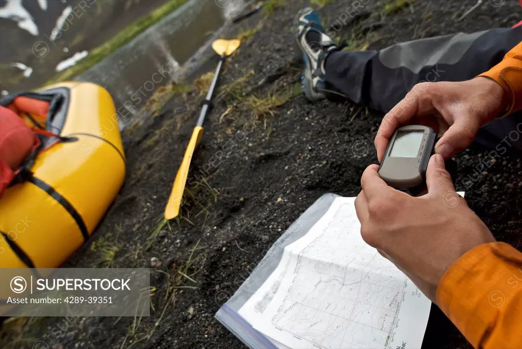 Close Up Of A Woman's Hands As She Checks Her Position On A Gps Before Heading Down The Aniakchak River In Aniakchak National Monument And Preserve In...