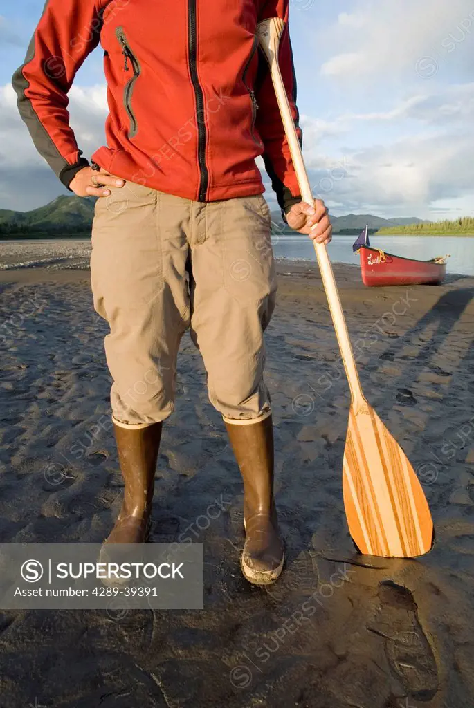 Close-Up Of Woman Holding A Canoe Paddle, Standing On The Bank Of The Yukon River In The Yukon-Charley Rivers National Preserve. Summer In Interior Al...