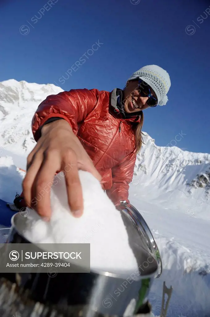 Woman melts snow for hot water at Kahiltna Base Camp on Mt. McKinley, Interior Alaska, Spring
