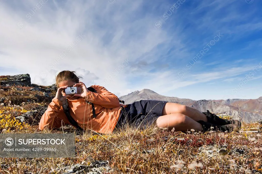 Hiker stops to take a picture near Noatak River in the Brooks Range, Gates of the Arctic National Park, Northwestern Alaska, above the Arctic Circle, ...
