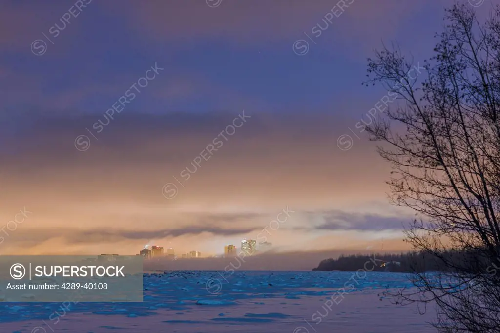 The Anchorage city skyline peeks out from behind the fog in this nighttime view from the tony Knowles Coastal Trail, Winter, Anchorage, Southcentral A...