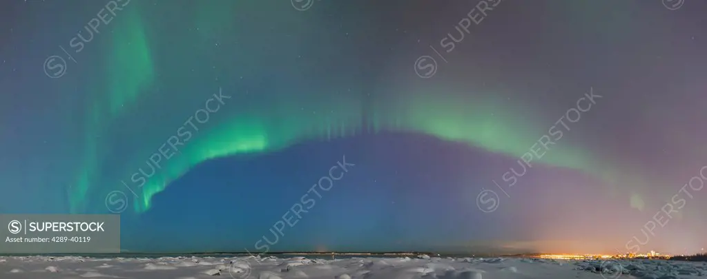 Panoramic of Northern Lights shine above the Anchorage city skyline and Knik Arm in this nighttime view from the tony Knowles Coastal Trail, Winter, A...