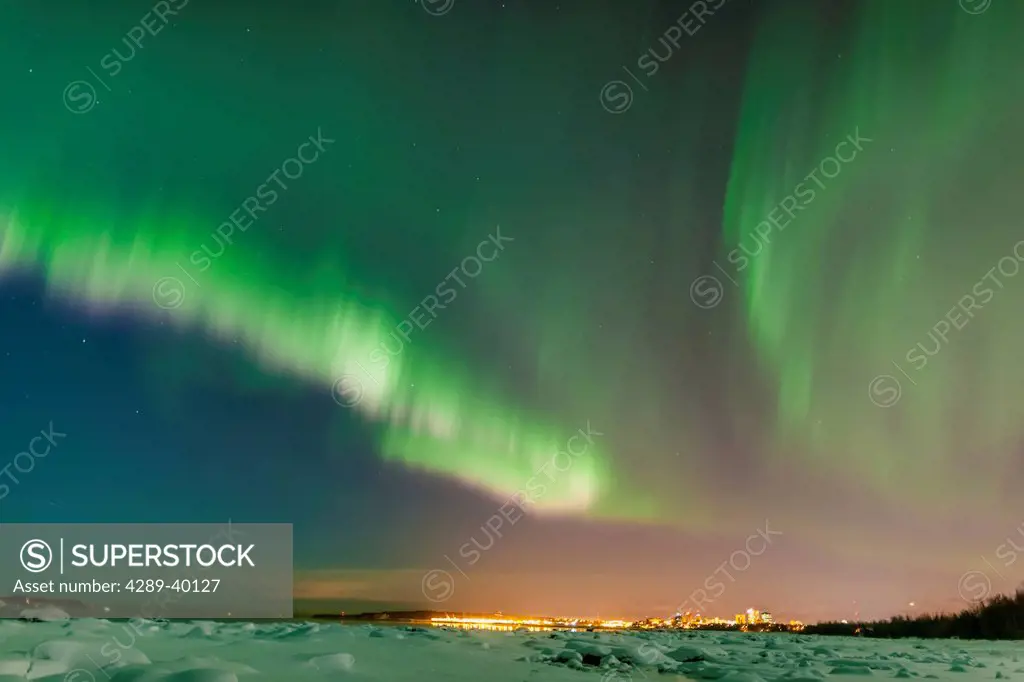 The Northern Lights shine above the Anchorage city skyline in this nighttime view from the Tony Knowles Coastal Trail, Winter, Anchorage, Southcentral...