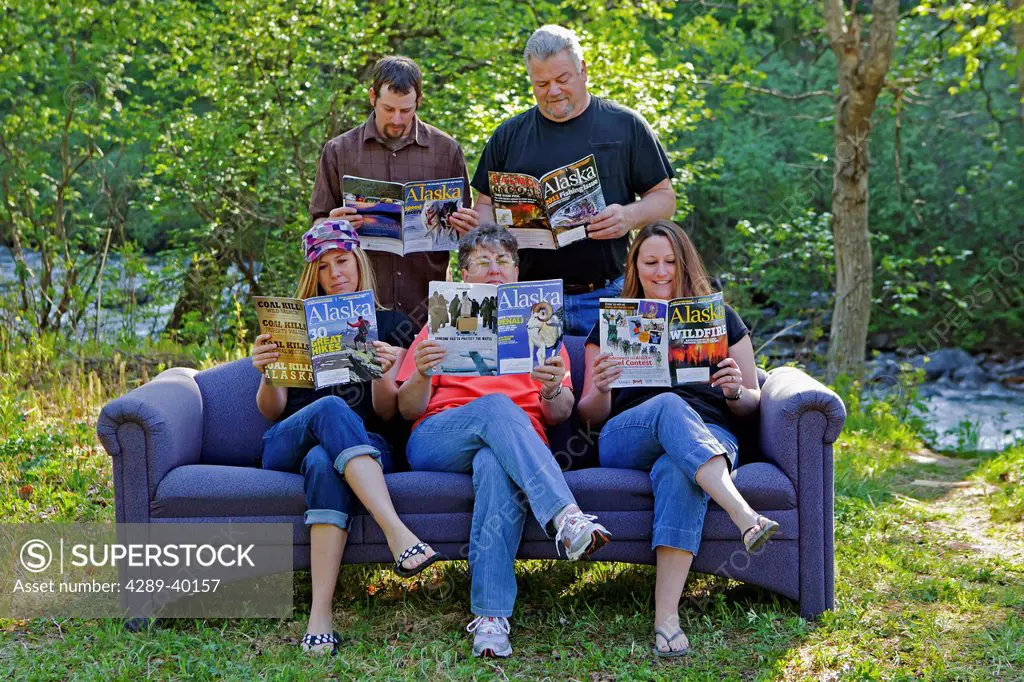 Family on outdoor couch reading Alaska Magazine in Hatcher Pass, Southcentral Alaska, Summer