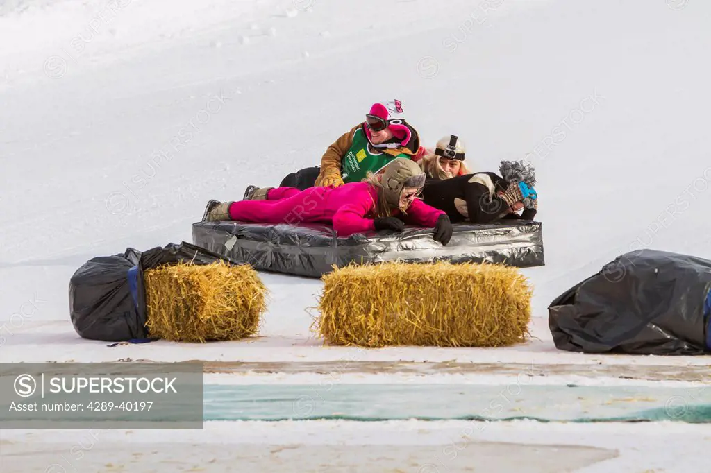 Competitors in the bed race slide down a ski slope and strike straw barriers at the Hilltop Ski area in Anchorage, Alaska during an event of the Ancho...
