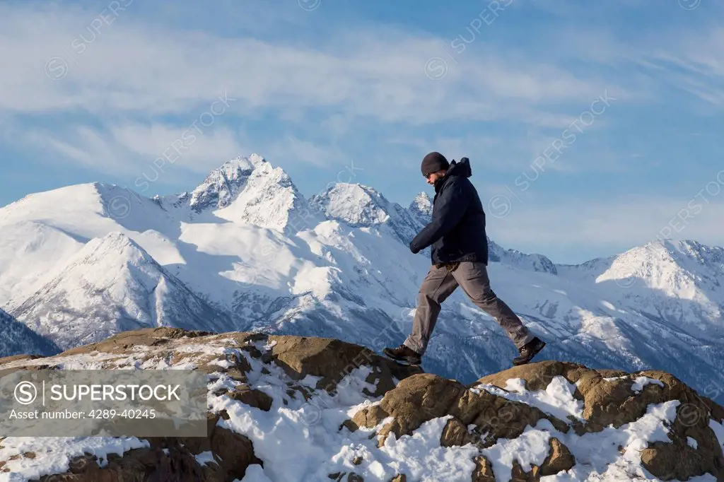 Man hiking the Bodenburg Butte with the snowcapped Chugach Mountains in the background, Matanuska Valley, Southcentral Alaska, Spring