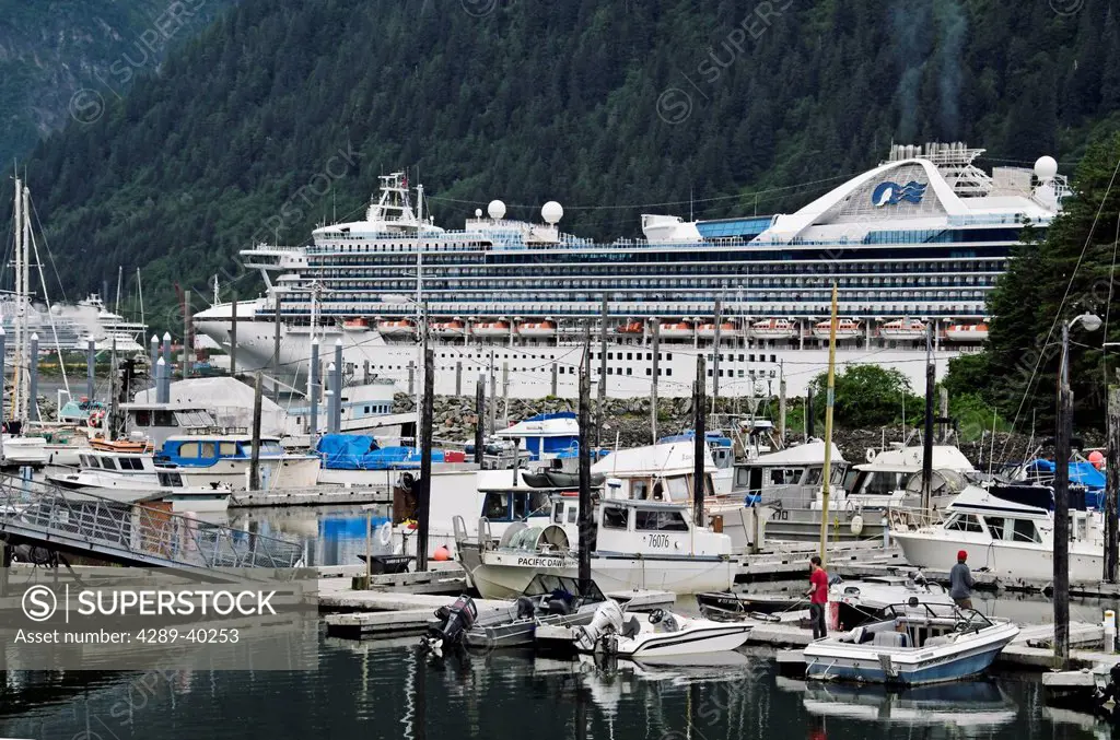 Princess Cruises ship Star Princess moored at Broadway Dock in Skagway Alaska; Small Boat Harbor in foreground with 2 people fishing off floating dock...