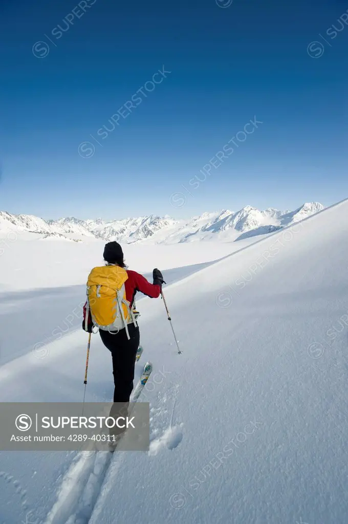 Female Backcountry Skier Skinning Across A Snowfield On Eagle Glacier, Chugach Mountains, Southcentral Alaska, Winter/N