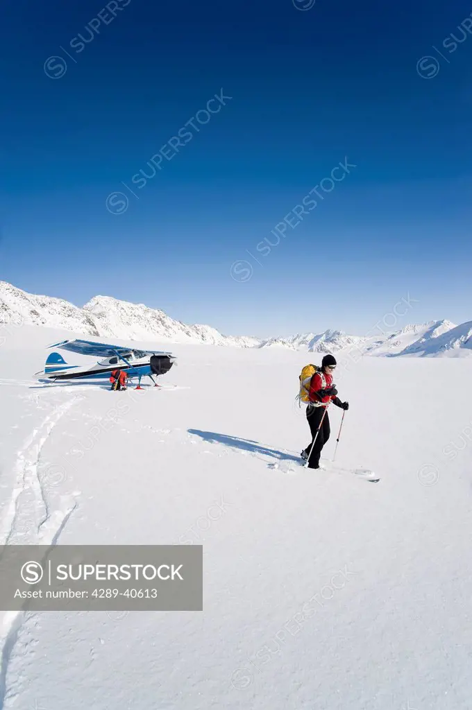 A Backcountry Skier And Snowboarder Get Dropped Off By A Cessna 170 Ski Plane On Eagle Glacier In The Chugach Mountains On A Sunny Day, Southcentral A...
