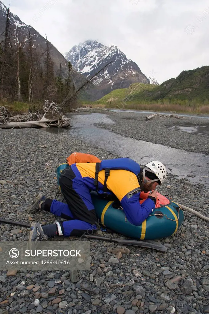 Man Inflating His Packraft Along The Gravel Banks Of The Eagle River In Southcentral Alaska