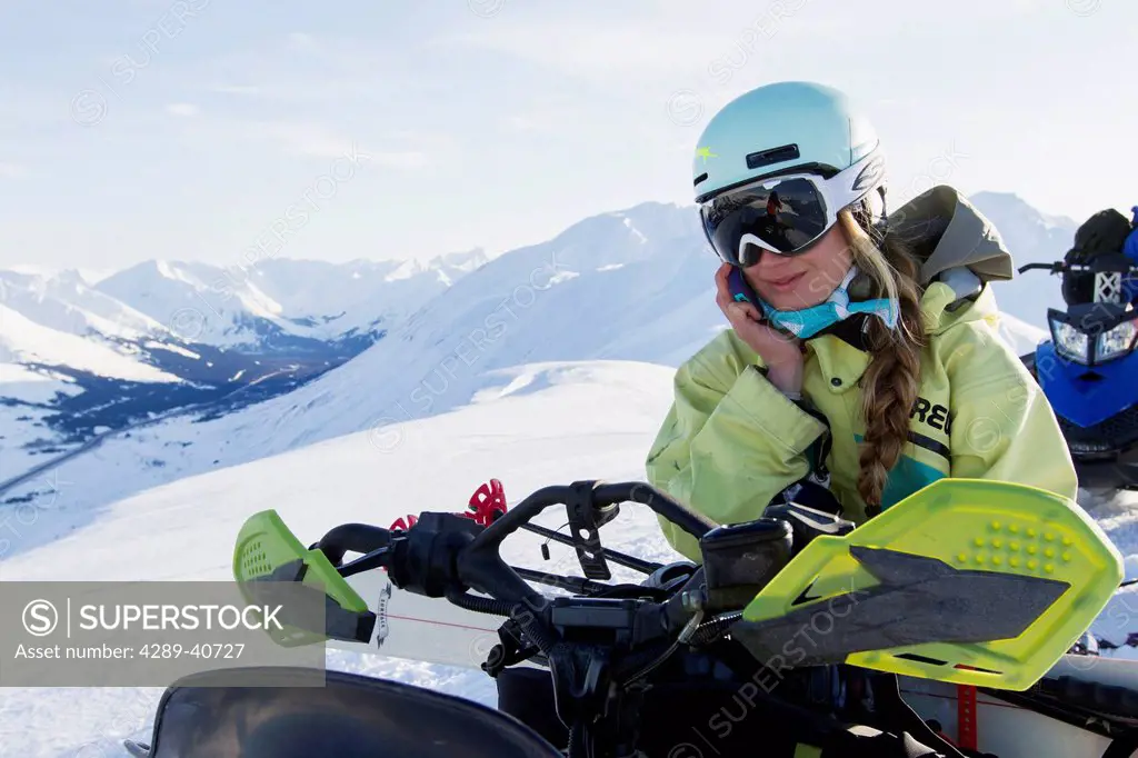 Sierra Quitiquit Talking On Her Smart Phone And Hanging Out While Backcountry Skiing By Snowmobile In Late Winter In The Chugach Mountains, Southcentr...