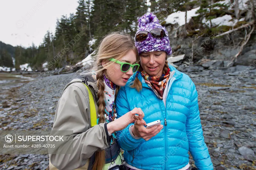 Sierra Quitiquit And Lizet Christiansen With Smartphone On The Beach In Whittier In Late Winter, Southcentral Alaska.