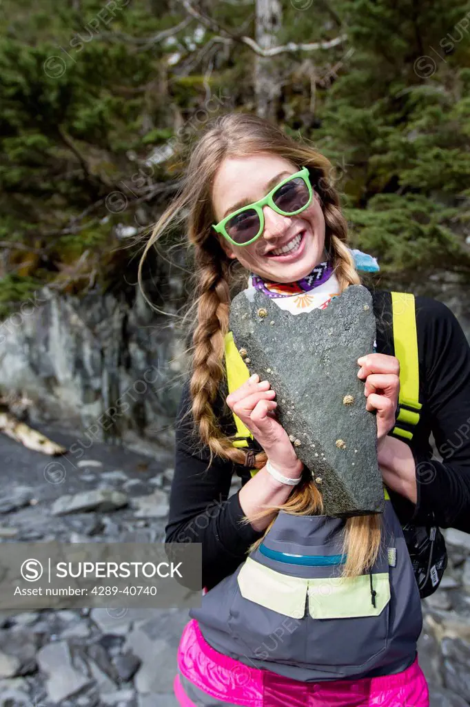 Sierra Quitiquit Holding Up A Heart Shaped Rock On The Beach In Whittier While On A Break During A Backcountry Ski Trip By Snowmobile In Late Winter, ...