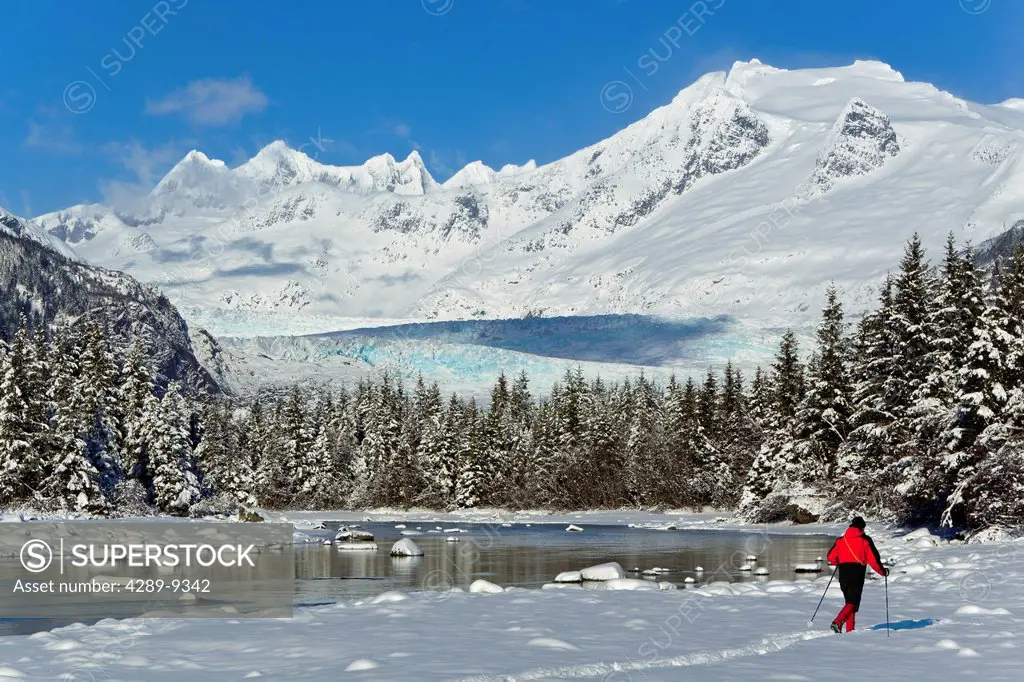 Person cross_country skiing in a winter landscape at Mendenhall River with Mendenhall Glacier and Towers in the background, Tongass National Forest, S...
