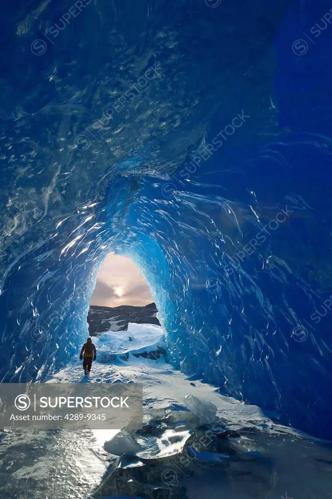 Man walks inside an ice cave of an iceberg frozen in Mendenhall Lake, Juneau, Southeast Alaska, Winter