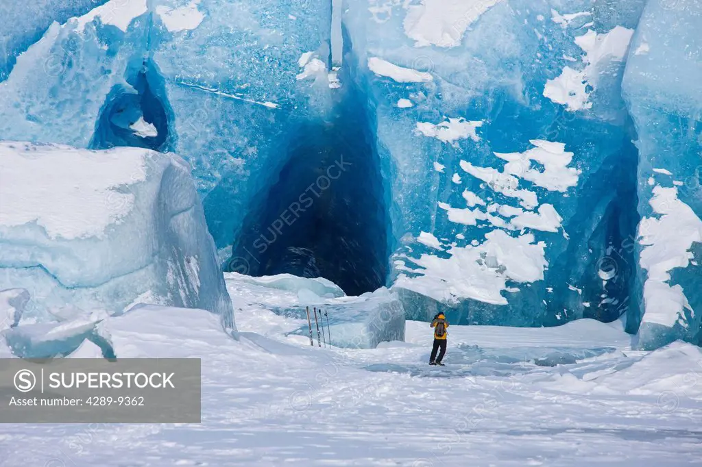 Man photographs a huge iceberg frozen into the surface of Mendenhall Lake, Juneau, Southeast Alaska, Winter