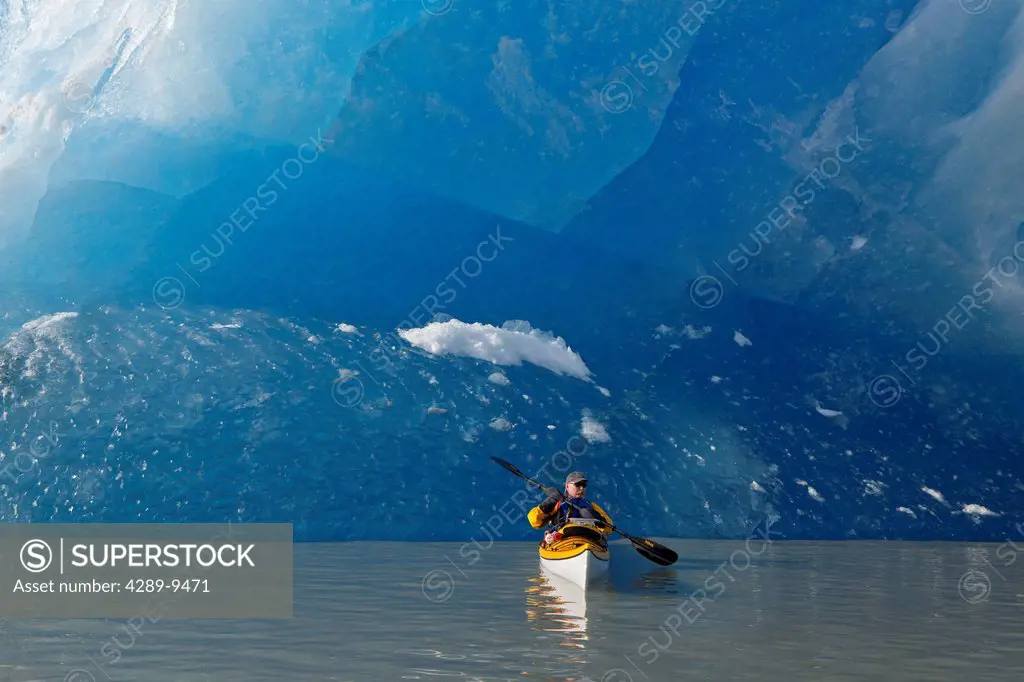 Sea kayaker on Mendenhall Lake with big blue iceberg in the background, Southeast Alaska, Summer