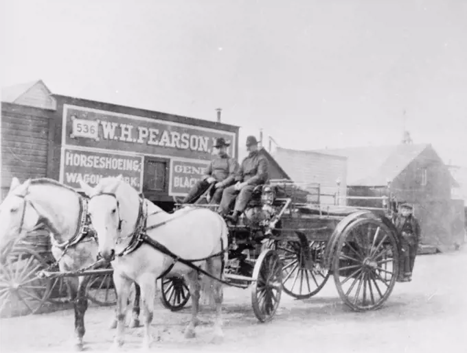 Historic image two men on a /nhorse drawn wagon with storefront behind them Nome Alaska