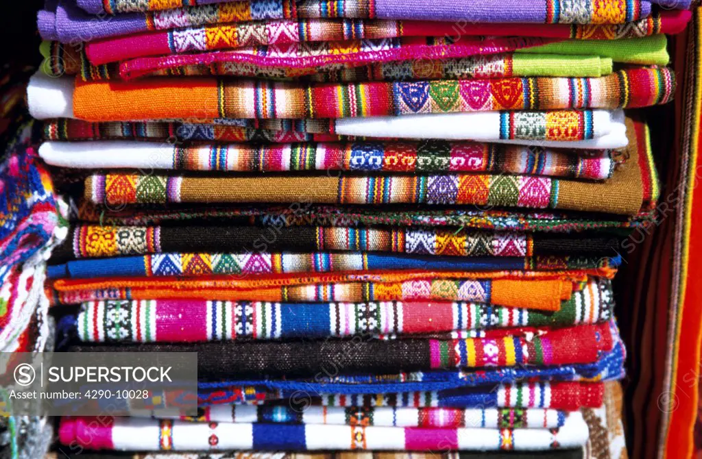 Pile of traditional colourful tablecloths on stall, Indian Market, Lima, Peru