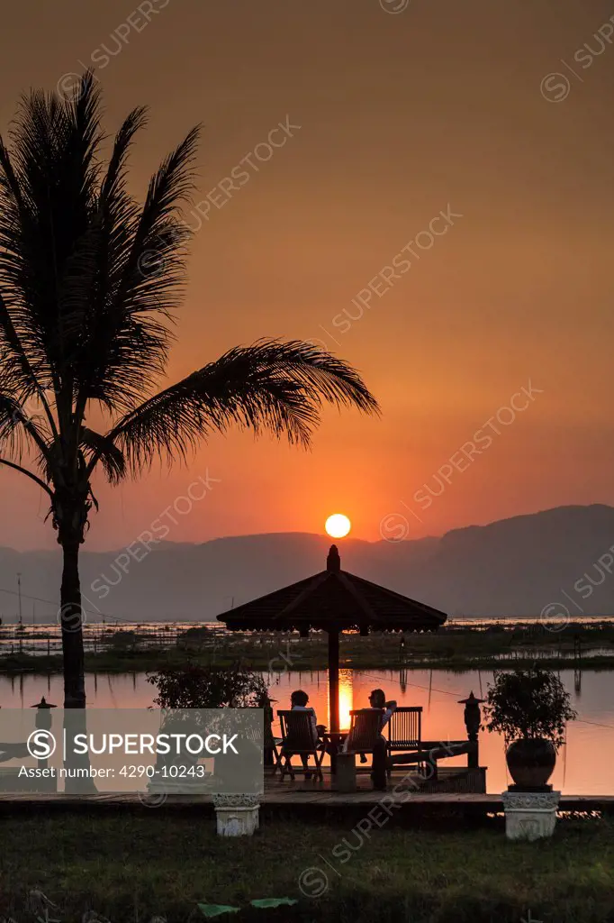 Tourists relaxing during a sunset over Inle Lake and Shan Taung Tan mountain, Nyaung Shwe, Shan State, Myanmar, (Burma)