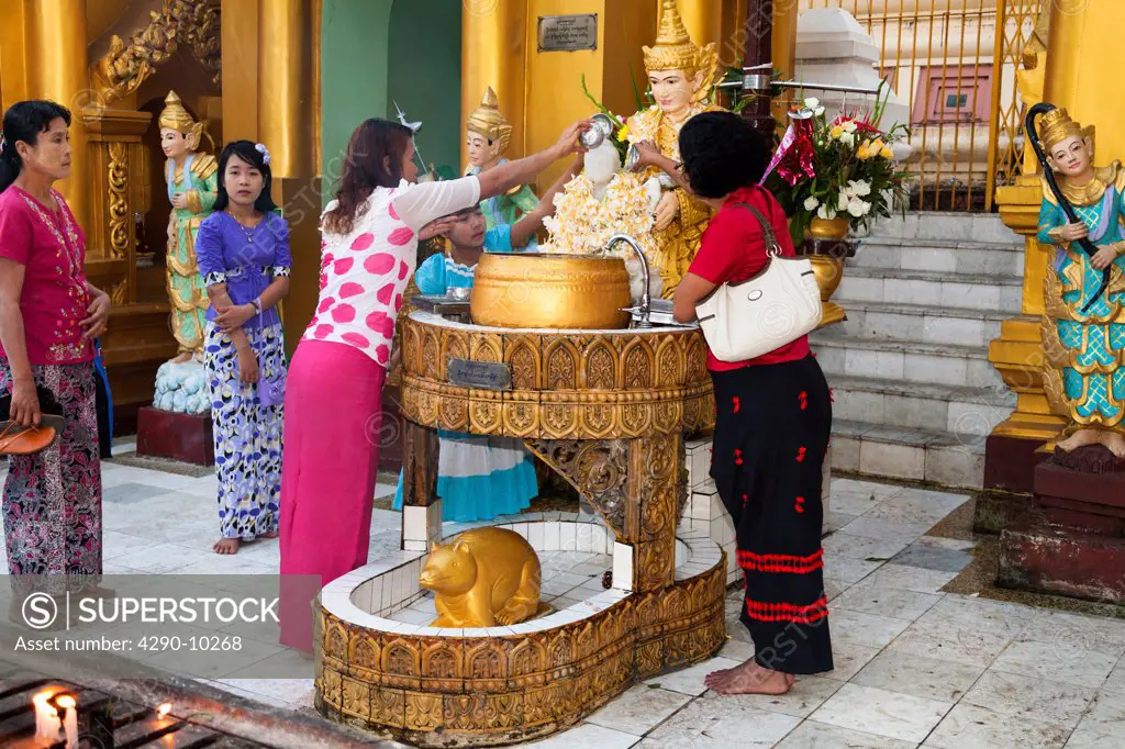 Worshippers pouring water onto a religious statue at Shwedagon Pagoda, Yangon, (Rangoon), Myanmar, (Burma)