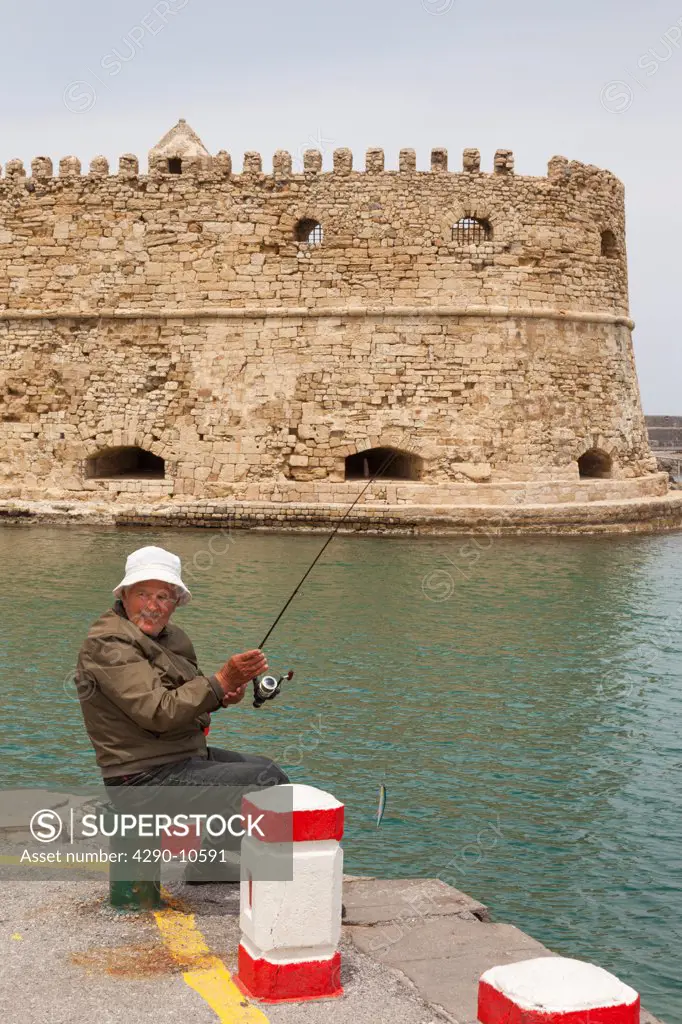 Man fishing beside Koules Fort in the Venetian Harbor, Heraklion, Crete, Greece