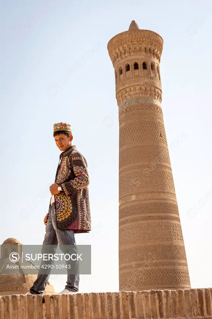 Young man beside Kalon Minaret, Kalon Mosque, also known as Kalyan Mosque, Poi Kalon, Bukhara, Uzbekistan