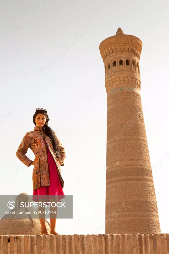 Young woman beside Kalon Minaret, Kalon Mosque, also known as Kalyan Mosque, Poi Kalon, Bukhara, Uzbekistan