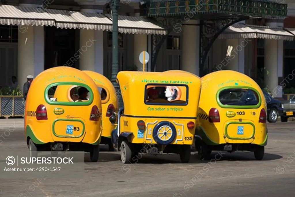 Several yellow three wheeled taxis parked at a taxi rank, Havana, Cuba