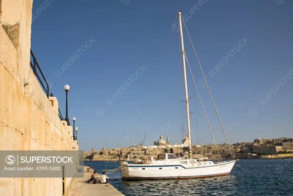 Yacht moored at the Sliema quayside, and views to Valletta, from Sliema, Malta