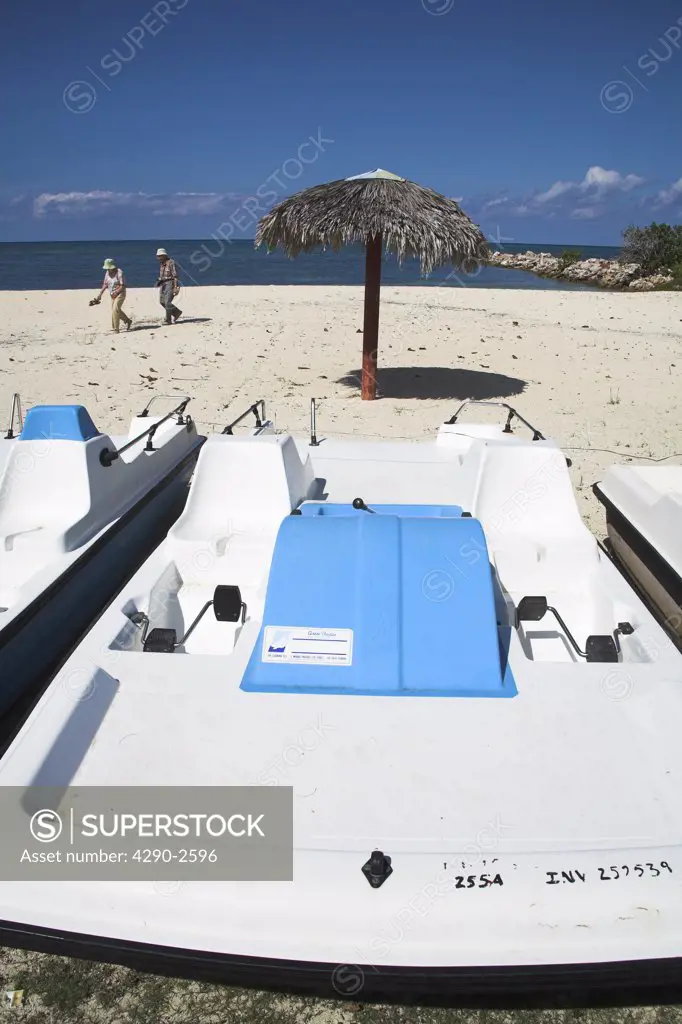 Pedalo boat, sun umbrella and people walking on a beach, Guardalavaca, Holguin Province, Cuba