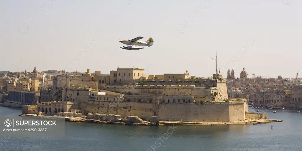 View of seaplane flying low over Valletta Harbour, Valletta, Malta