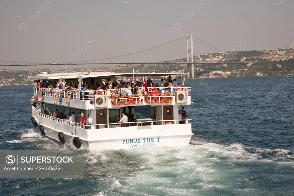 Tourists cruising on the Yunus Tur I on the Bosphorus, approaching the Bosphorus Bridge, Istanbul, Turkey