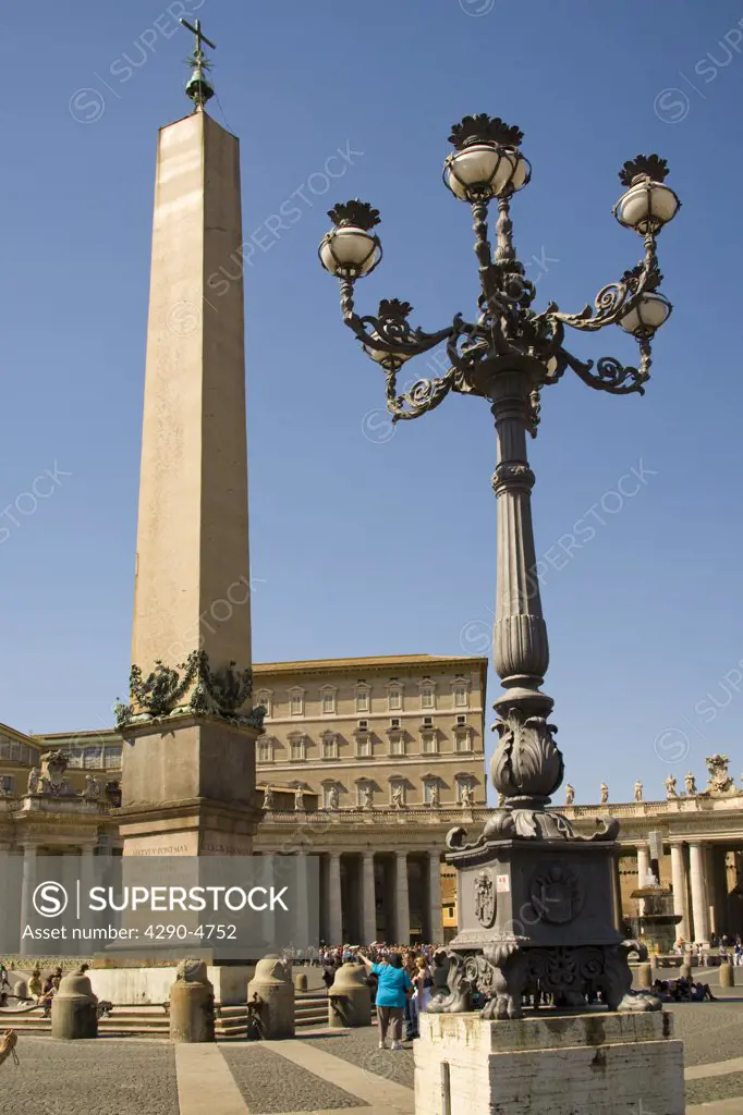 Obelisk, streetlamp and tourists in Saint Peters Square, Piazza San Pietro, Vatican City, Rome, Italy
