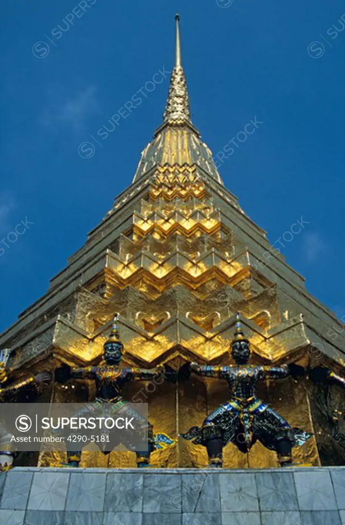 Guardian mythical demons supporting golden chedi, Grand Palace, Bangkok, Thailand