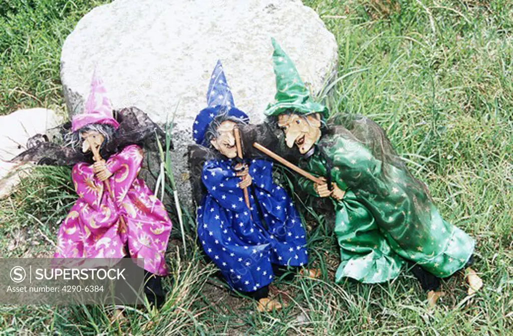 Three colourful witches for sale on display in the grass, Torcello, Venice, Italy