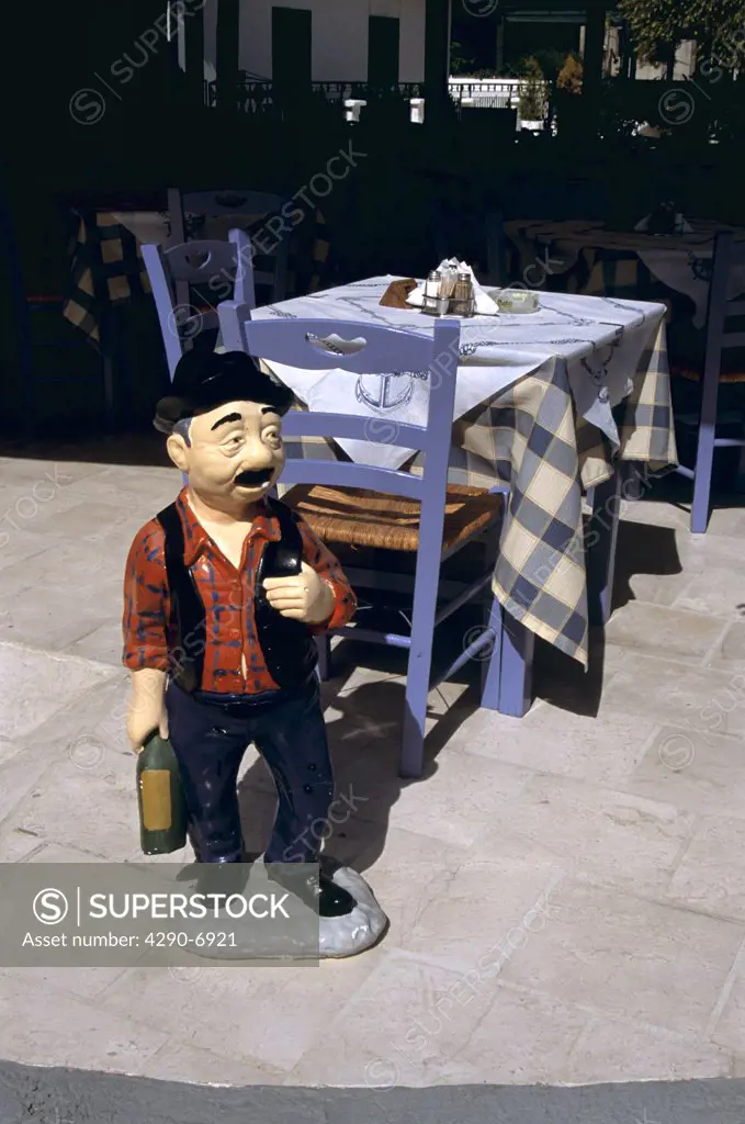 Model of a waiter in front of table and chairs outside a restaurant, Agia Efimia, Kefalonia, Greece