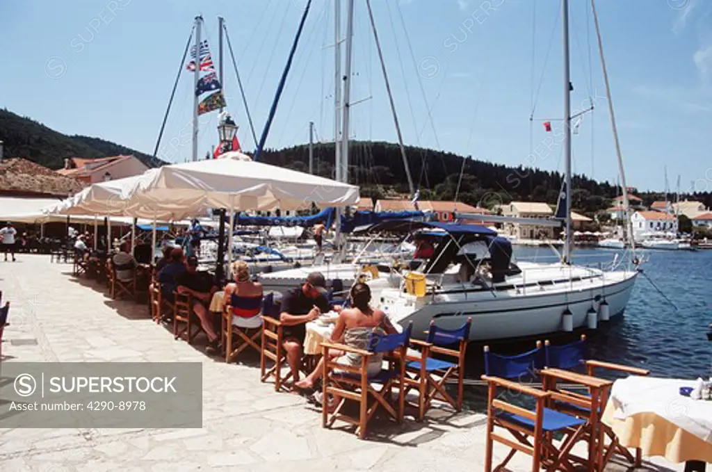 Tourists dining at tables on quayside restaurant, Fiskardo, Kefalonia, Greece