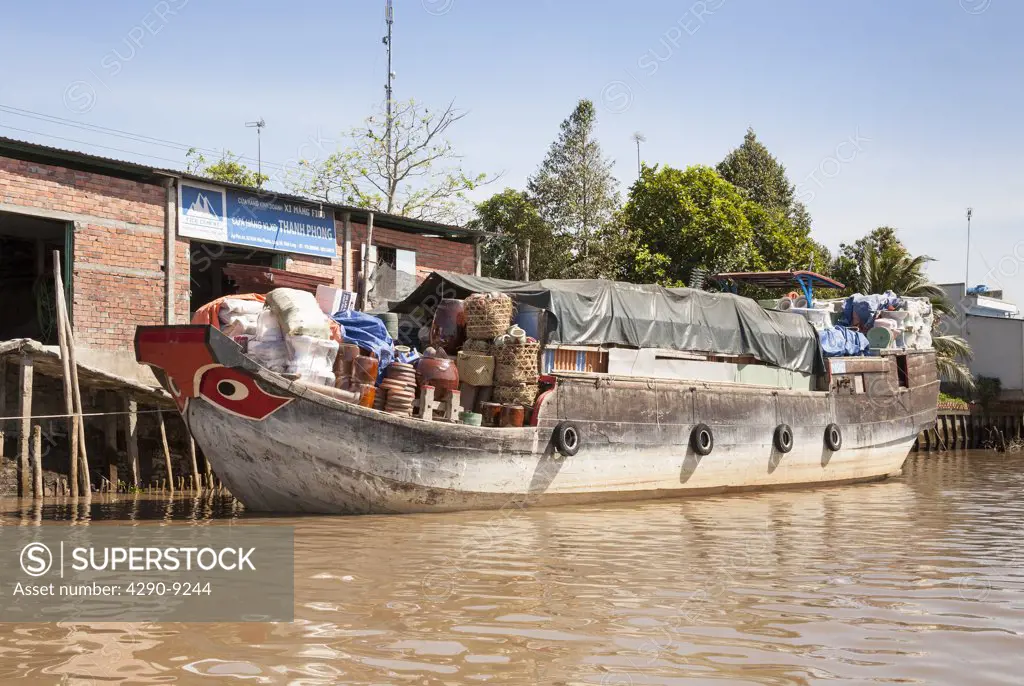 Vietnam, Mekong River Delta, Vinh Long, fully laden cargo boat moored beside building