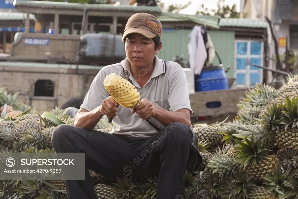 Vietnam, Mekong River Delta, Cai Rang, near Can Tho, man cutting pineapple in floating market