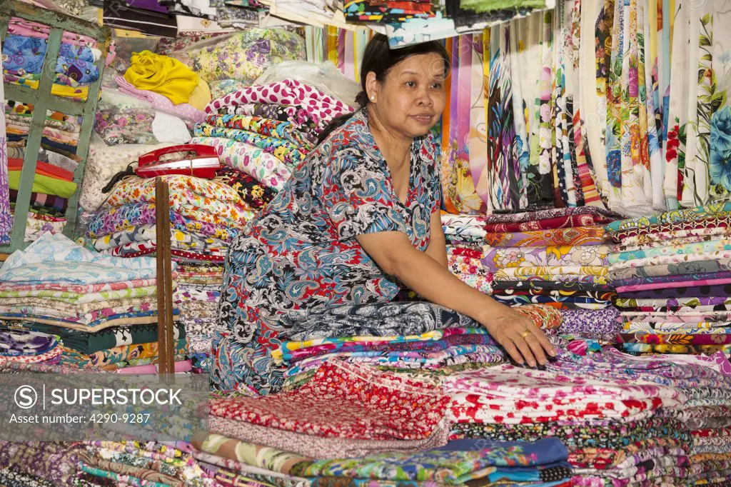 Vietnam, (Saigon), Ho Chi Minh City, Market trader selling fabrics inside Ben Thanh Market
