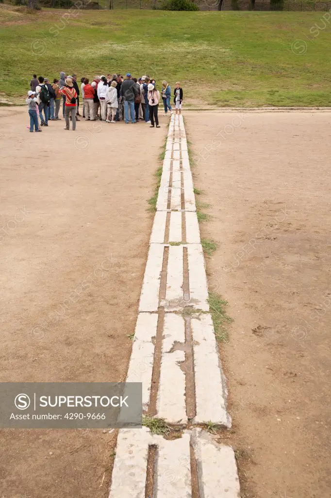 Tourists at the starting line of the original Olympic Stadium, Olympia, Greece