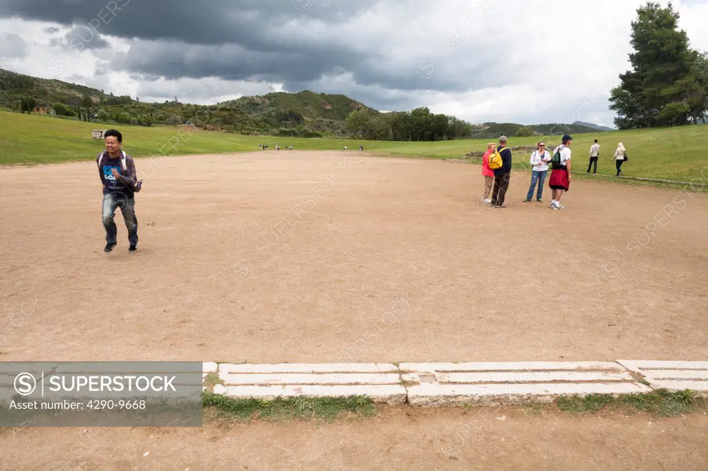 Tourists at the starting line of the original Olympic Stadium, Olympia, Greece