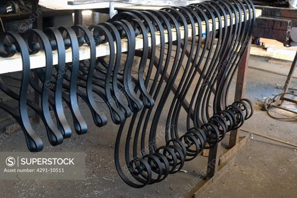 Crafted metal scrolls for gate drying on rack after treatment with anti-rust primer prior to assembly