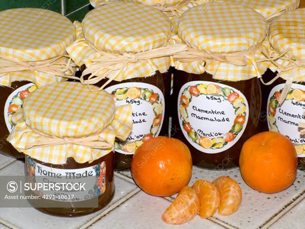 Close up of home-made clemantine marmalade in glass jars with yellow and white checked gingham tops