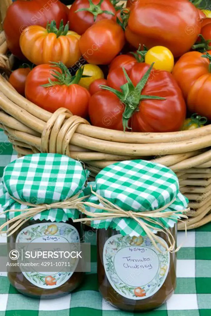 Still life of tomatoes in basket and jars of tomato chutney